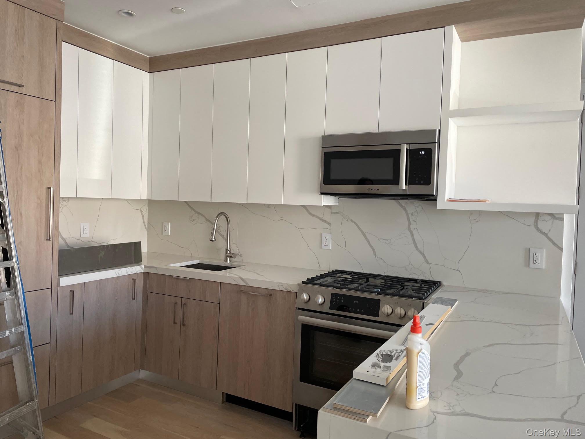 19-14 21st Road, Unit 2A Queens, NY 11105 - Photo 10 of 19 a kitchen with stainless steel appliances a stove a microwave and sink