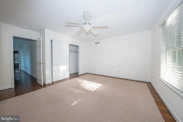 a view of a big room with windows and chandelier fan