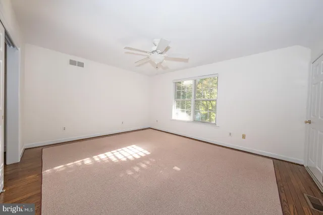an empty room with windows and fan
