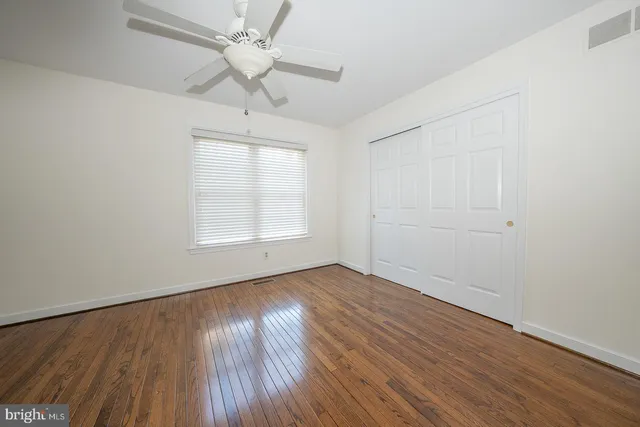 an empty room with wooden floor chandelier fan and windows