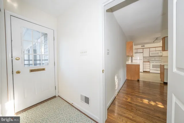 a view of a hallway with wooden floor and a living room