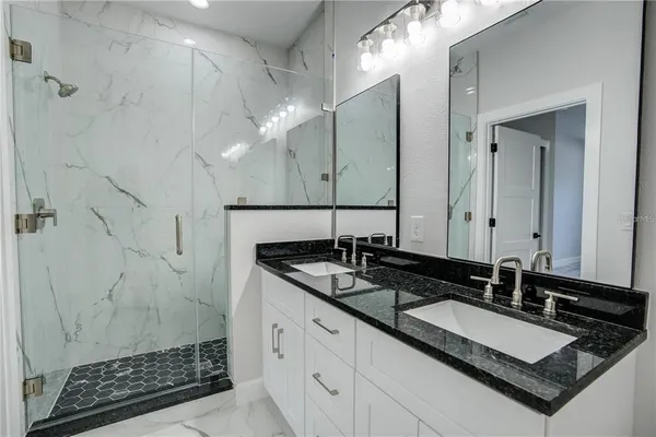 a bathroom with a granite countertop sink a mirror and a shower