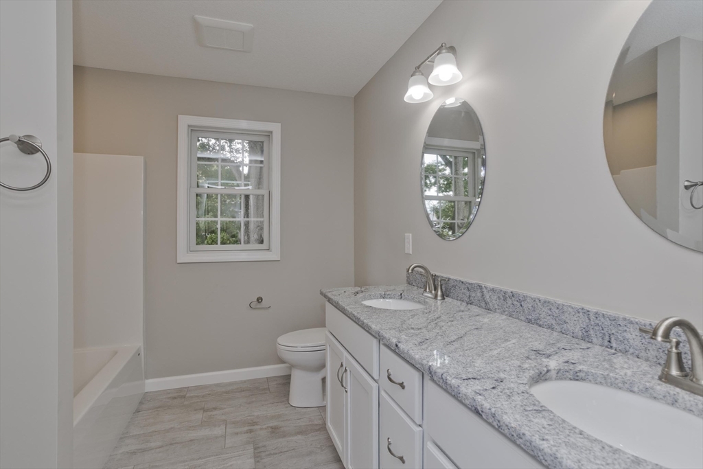 34 Chilson Street Springfield, MA 01118 - Photo 17 of 23 a bathroom with a granite countertop toilet a sink and a mirror