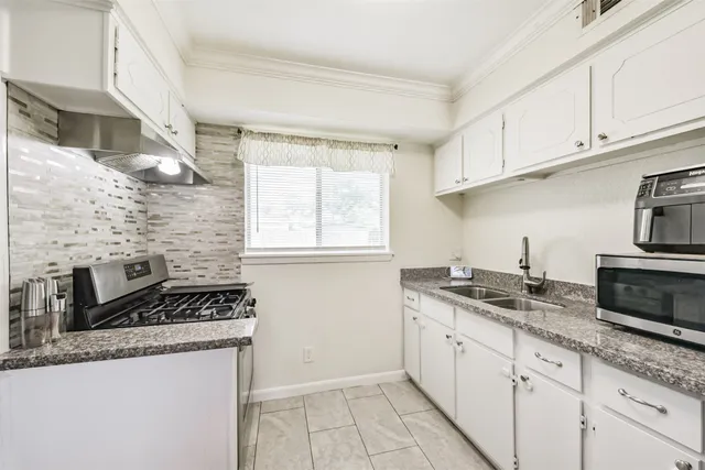 a kitchen with stainless steel appliances granite countertop a sink a refrigerator and white cabinets
