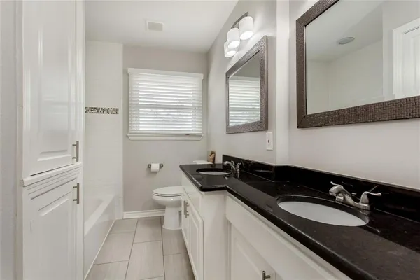 a bathroom with a granite countertop sink a toilet a mirror and shower