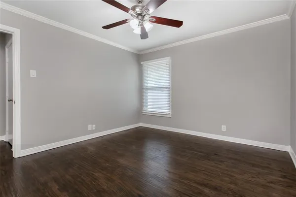 an empty room with wooden floor chandelier fan and windows