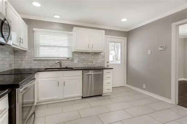 a kitchen with granite countertop white cabinets white appliances with a sink and dishwasher