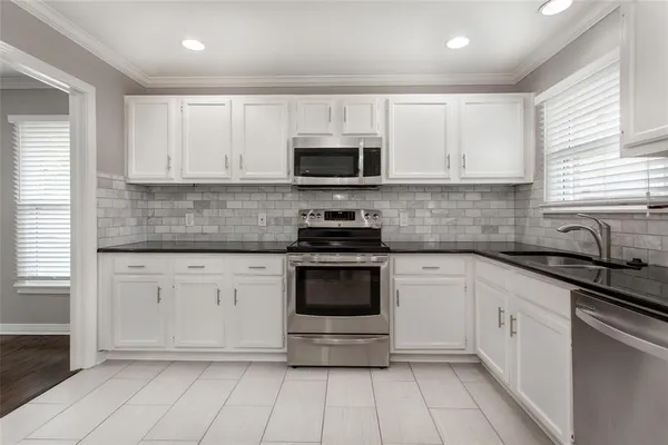 a kitchen with stainless steel appliances granite countertop white cabinets granite counter tops and a window