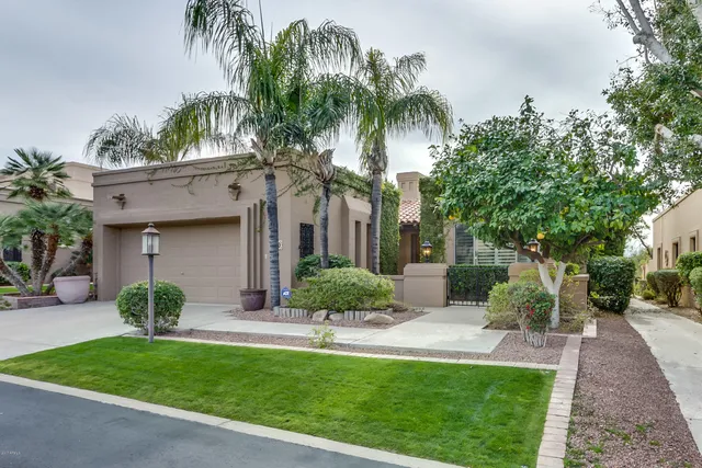 a front view of a house with a garden and palm trees