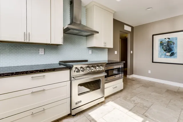a kitchen with stainless steel appliances granite countertop white cabinets and a stove