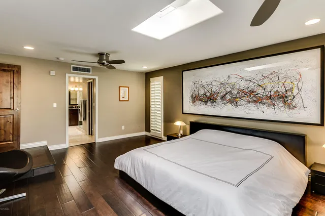 a bedroom with a large bed and a painting on the wall