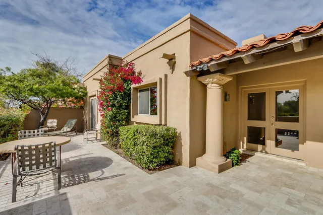 front view of a house with a chairs and table in a patio
