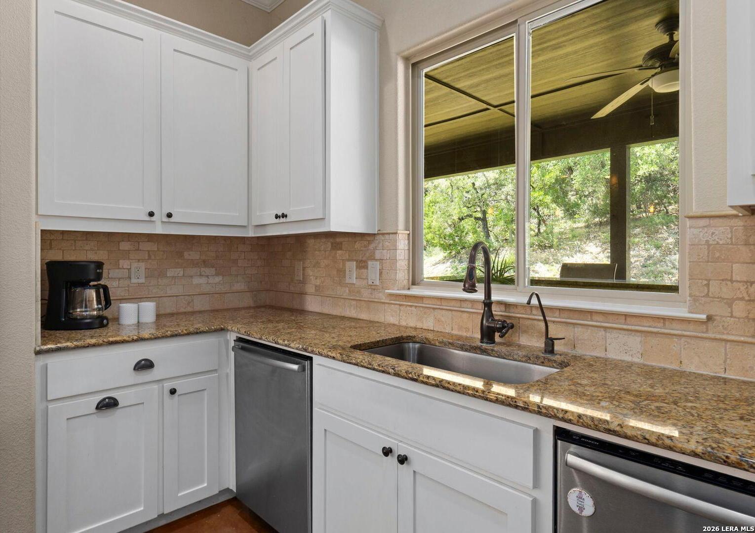 786 Shepherd's Crook Helotes, TX 78023 - Photo 9 of 36 a kitchen with granite countertop white cabinets and a window