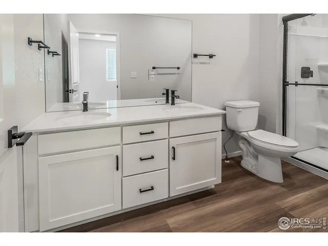 a bathroom with a toilet sink double vanity and mirror