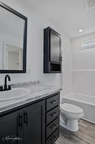 a bathroom with a granite countertop toilet sink and mirror