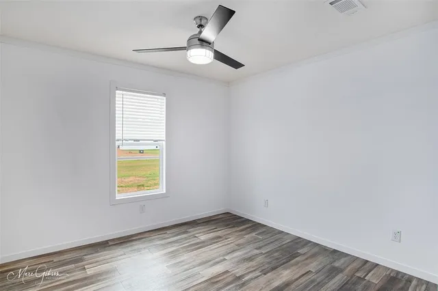 an empty room with a window and ceiling fan
