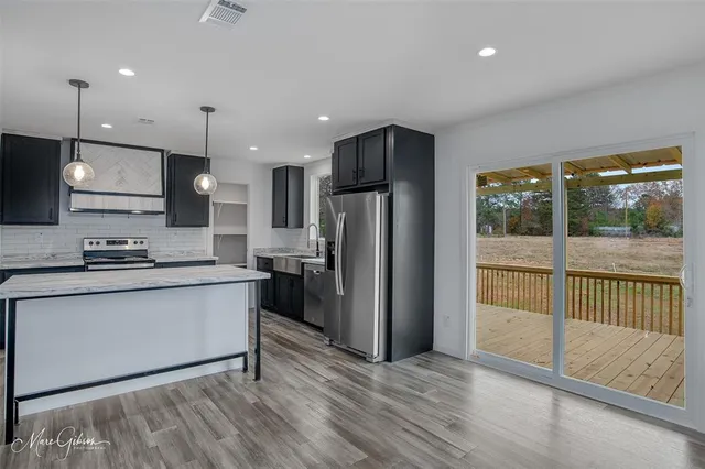 a kitchen with stainless steel appliances granite countertop a refrigerator a sink a stove and a wooden floors