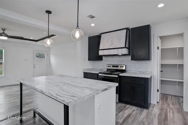 a kitchen with stainless steel appliances granite countertop wooden cabinets a stove a sink and a refrigerator