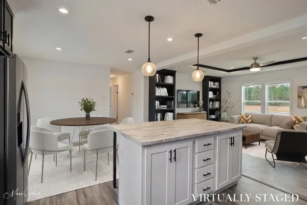 a kitchen with stainless steel appliances kitchen island granite countertop a table chairs and a chandelier