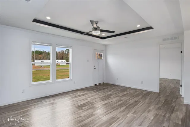 a view of an empty room with wooden floor and a window