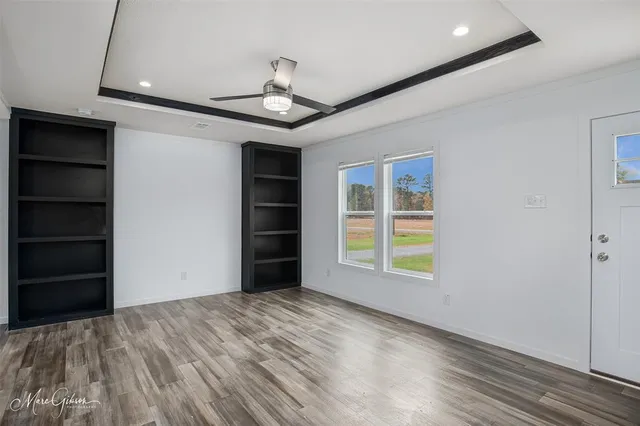 a view of an empty room with a window and wooden floor