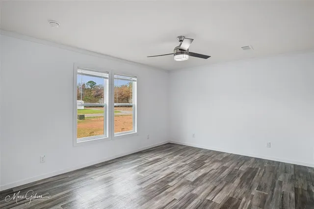 an empty room with a window and ceiling fan