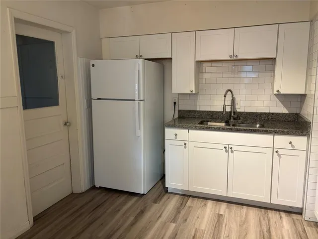a kitchen with granite countertop a sink a refrigerator a stove and white cabinets