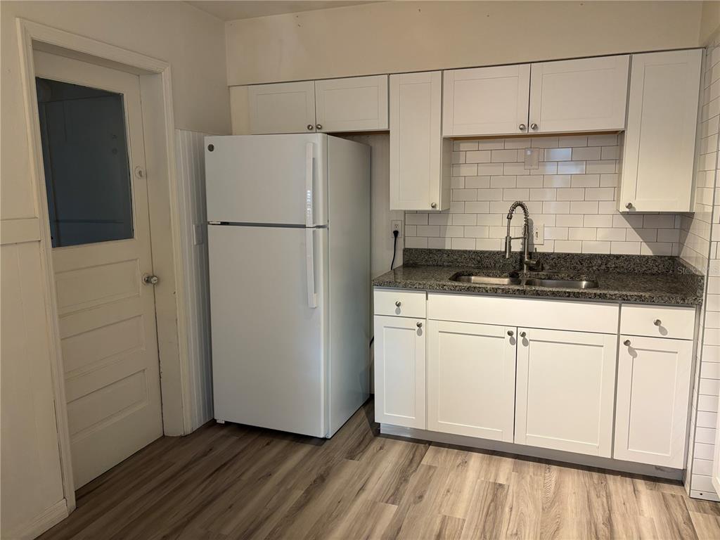 1102 Sunset Point Road, Unit 6 Clearwater, FL 33755 - Photo 11 of 31 a kitchen with granite countertop a sink a refrigerator a stove and white cabinets