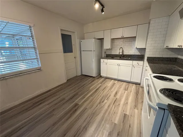 a kitchen with granite countertop white cabinets and white appliances