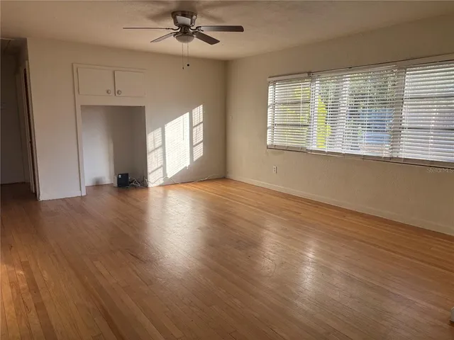 a view of an empty room with wooden floor and a window
