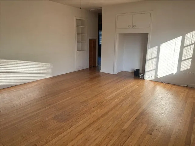 a view of an empty room with wooden floor and a window