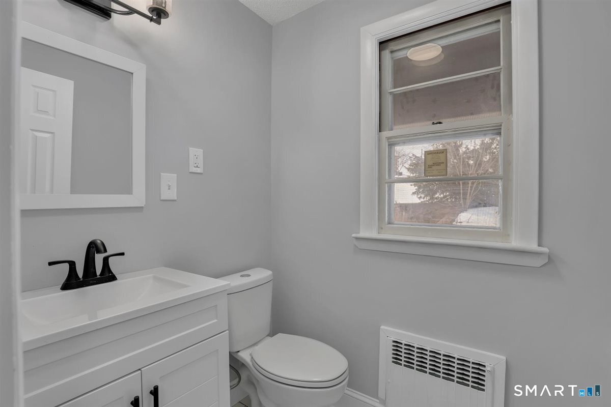 909 Randolph Road Middletown, CT 06457 - Photo 16 of 24 a bathroom with a toilet a sink a vanity and mirror