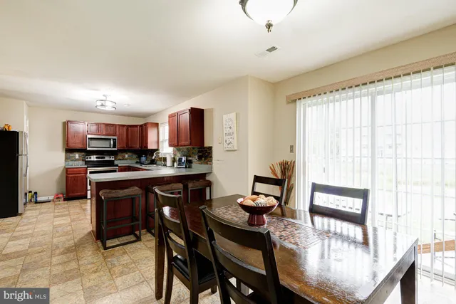 a kitchen with stainless steel appliances granite countertop a stove a refrigerator a sink a dining table and chairs