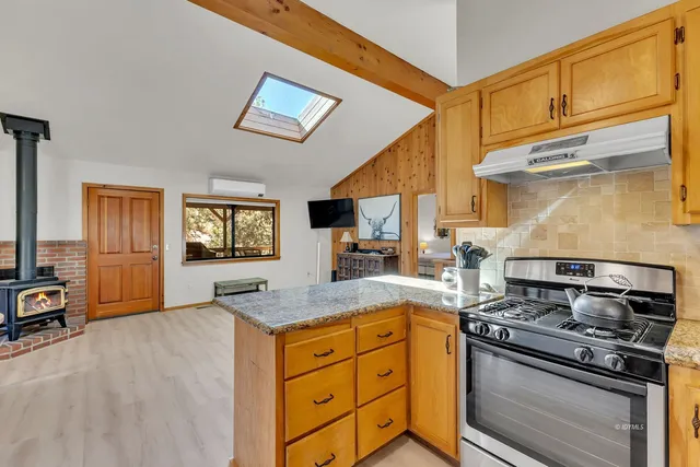 a kitchen with granite countertop stainless steel appliances a refrigerator a stove a sink a dining table and chairs with wooden floor