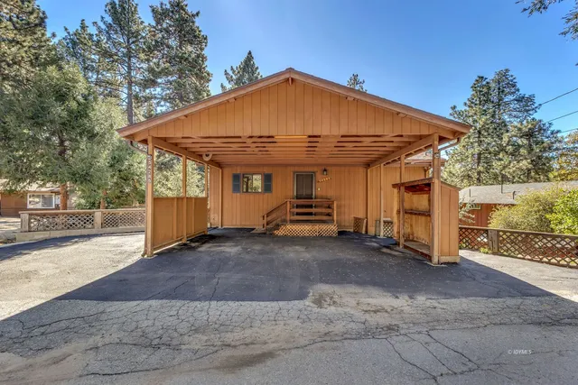 a view of a wooden house with a large trees and a big yard