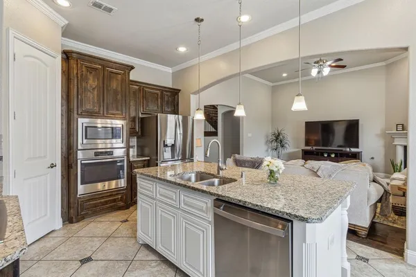 a kitchen with kitchen island granite countertop a refrigerator and microwave