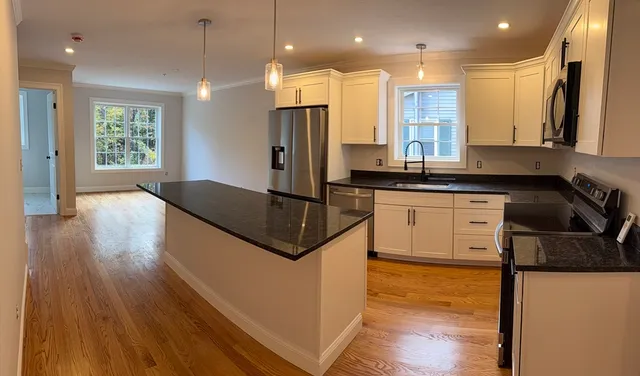 a kitchen with stainless steel appliances granite countertop a sink a stove and a wooden floors