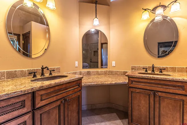a bathroom with a granite countertop double vanity and a mirror
