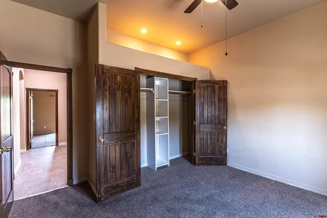 an empty room with closet and a chandelier fan