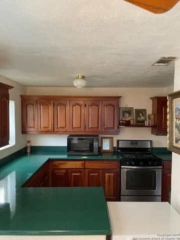 a kitchen with stainless steel appliances granite countertop a stove a sink and a microwave
