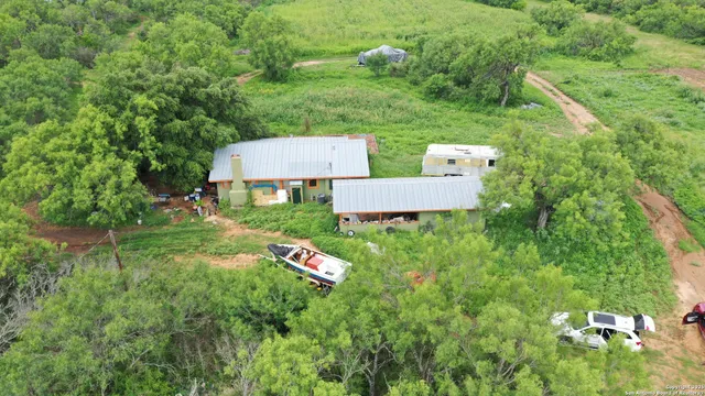 an aerial view of residential house with outdoor space and trees all around