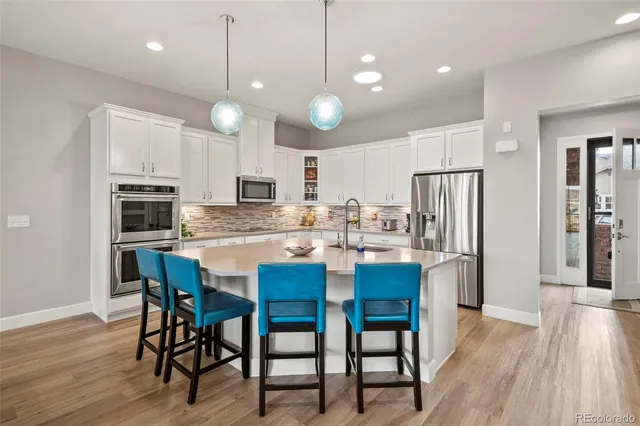 a kitchen with stainless steel appliances a dining table chairs refrigerator and microwave