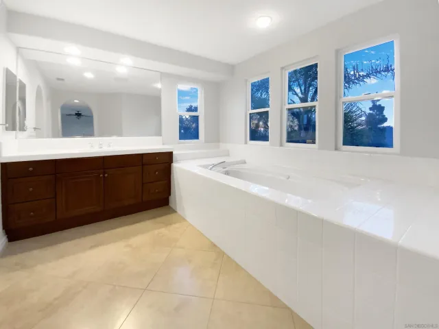 a spacious bathroom with a tub sink and mirror