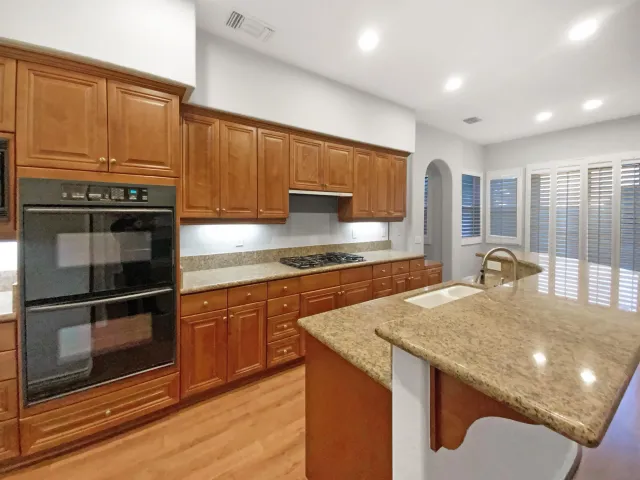 a kitchen with granite countertop a stove a sink and a microwave