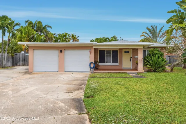a front view of a house with a yard and potted plants