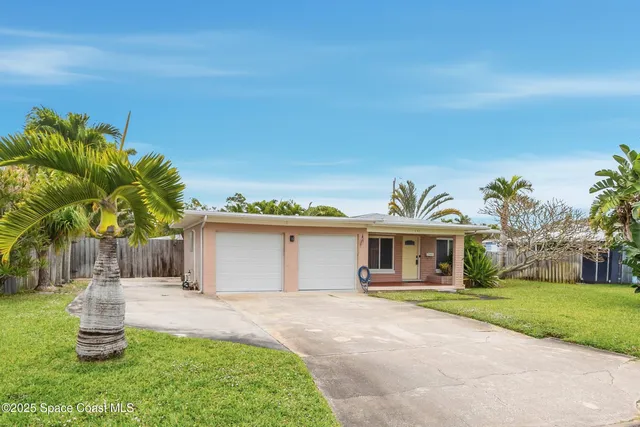 a front view of a house with a garden and tree
