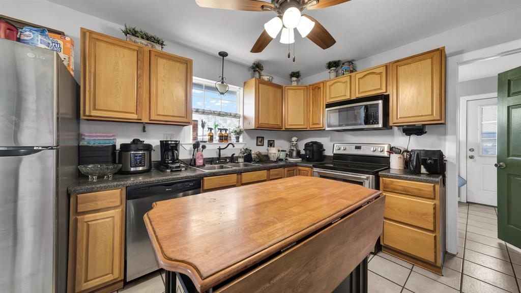 11500 Bowden Road Lipan, TX 76462 - Photo 22 of 32 Kitchen with light tile patterned flooring, ceiling fan, stainless steel appliances, hanging light fixtures, and sink