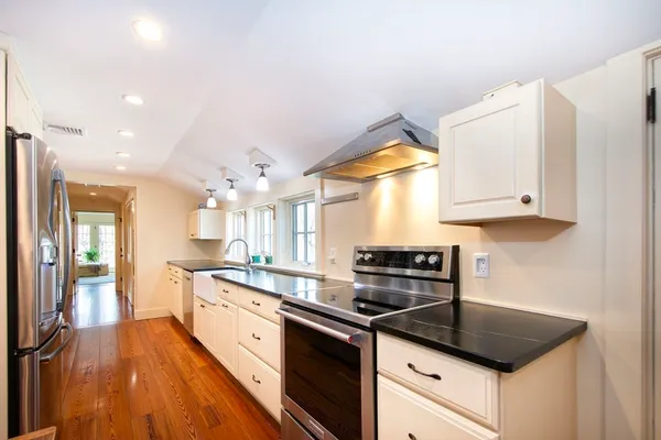 a kitchen with granite countertop a stove a sink and a granite counter tops with wooden floors