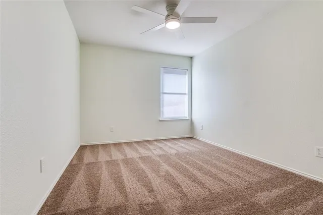 an empty room with a window and ceiling fan