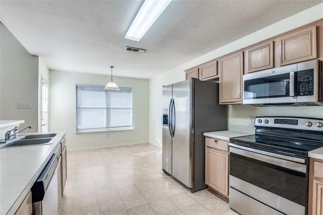 a kitchen with stainless steel appliances granite countertop a refrigerator stove and sink